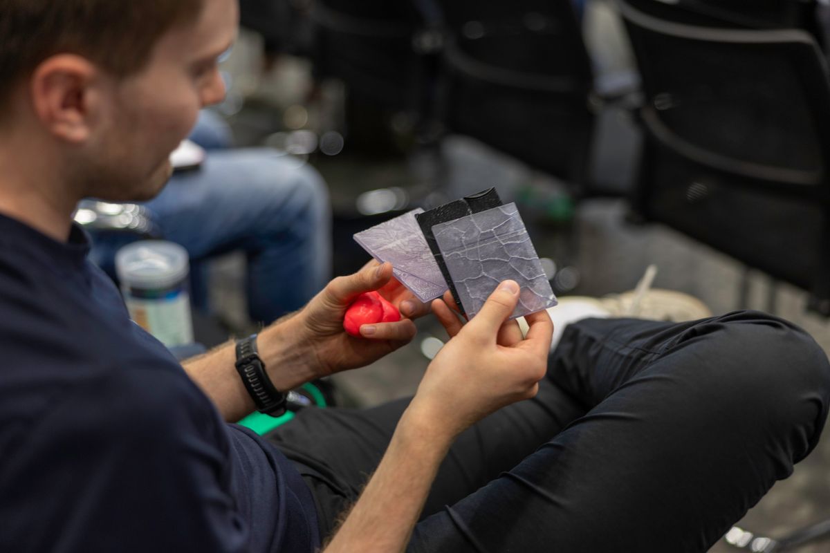 Hands holding 3D-printed tactile lithographs of biological surface textures